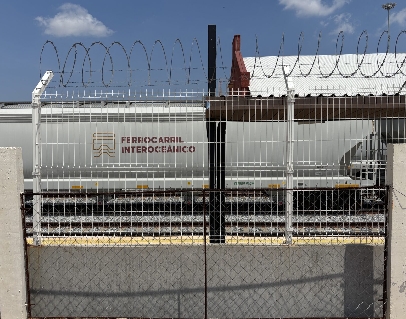 Train car behind barbed wire fence.